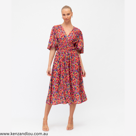 The enchanting floral dress features a captivating burst of blossoms that dance gracefully across the fabric. Its whimsical design is elevated by charming balloon sleeves, adding a playful and romantic touch. This garment effortlessly combines timeless elegance with a modern twist, making it the perfect choice for any special occasion. 100% Polyester Kenz&Lou front view